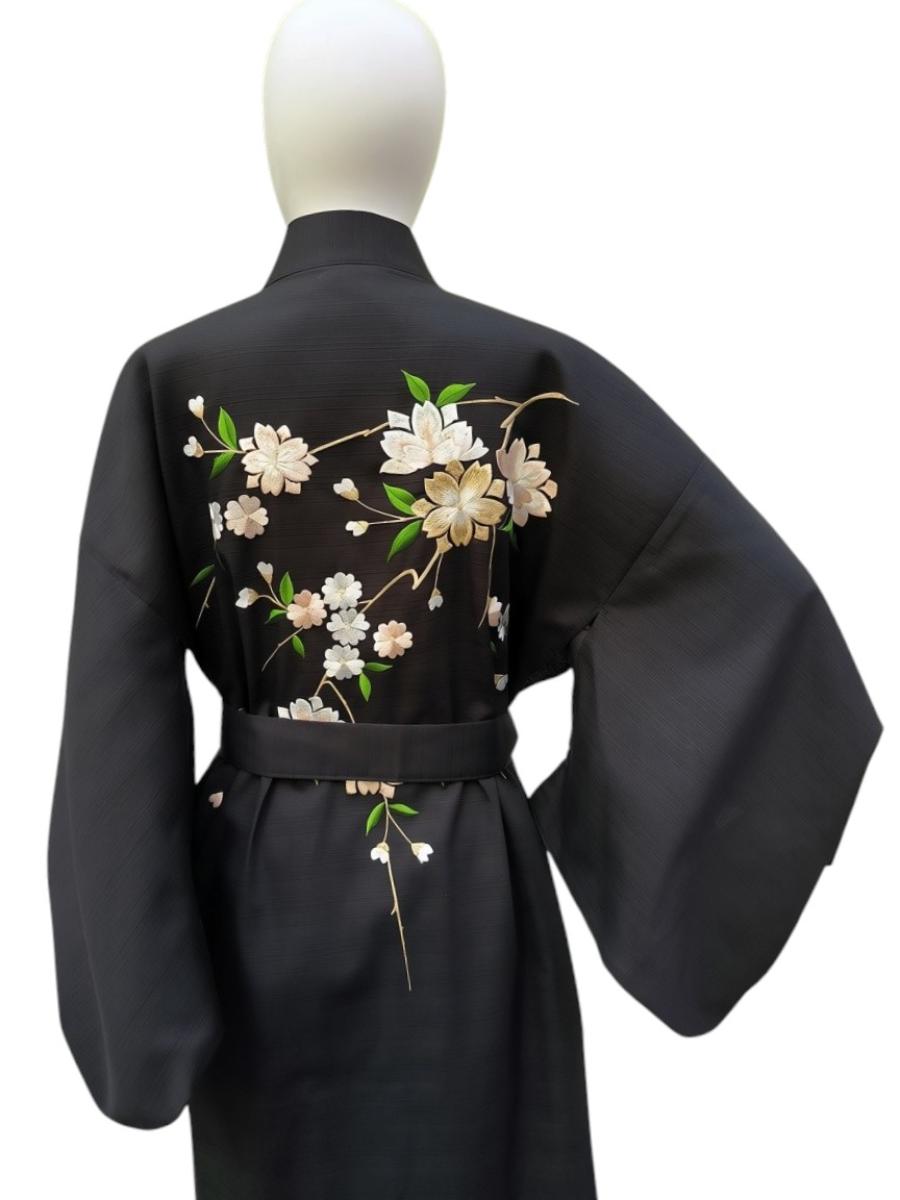 Kimono mit Detail der Seidenstickerei mit weißen und goldenen Kirschblüten auf schwarzem Kimono